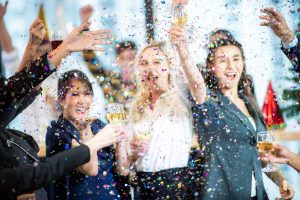 Miembros felices de un equipo de trabajo de una empresa celebrando un logro anual levantando su copa en eventos para Pymes.