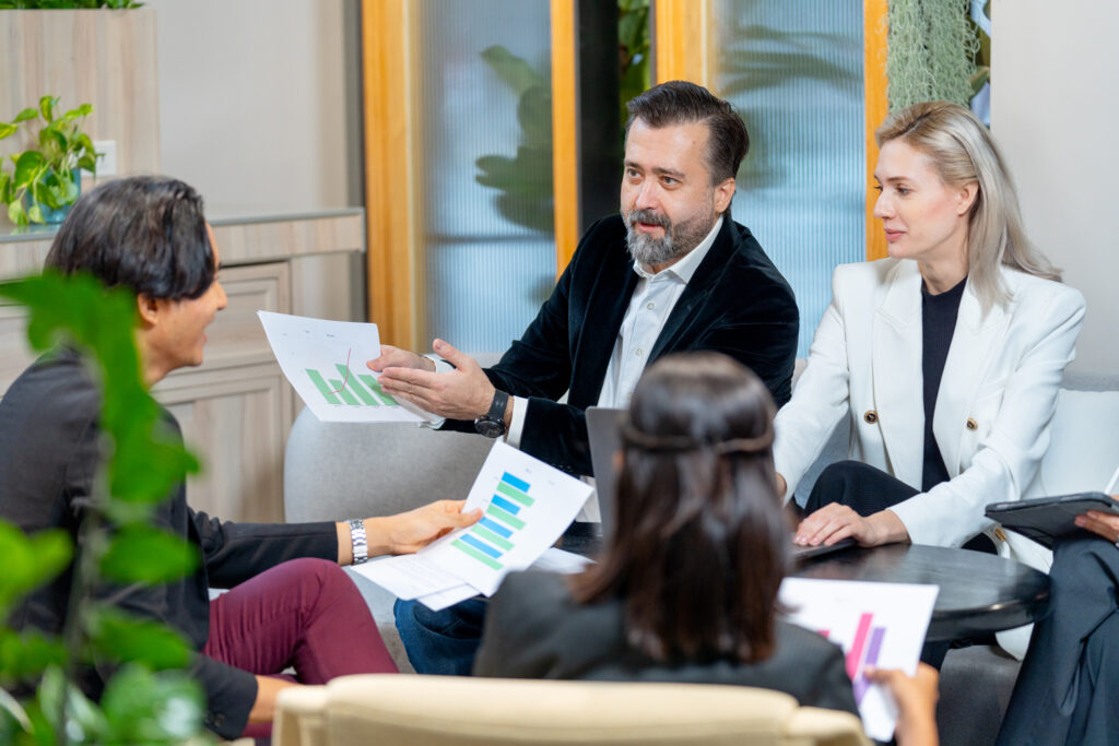 Grupo profesional revisa gráficos impresos durante una sesión de formación de PYMES en un ambiente moderno y colaborativo.
