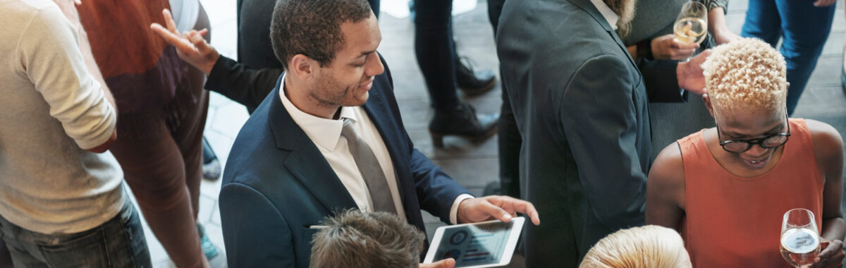 networking-monterrey-1 Vista aérea de personas conversando en evento de Networking Monterrey; hombre con tablet y trajes formales visibles.