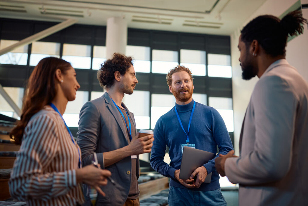 Conversación casual entre colegas en Networking Monterrey, mientras tienen un café en mano, gafetes visibles y ambiente relajado.