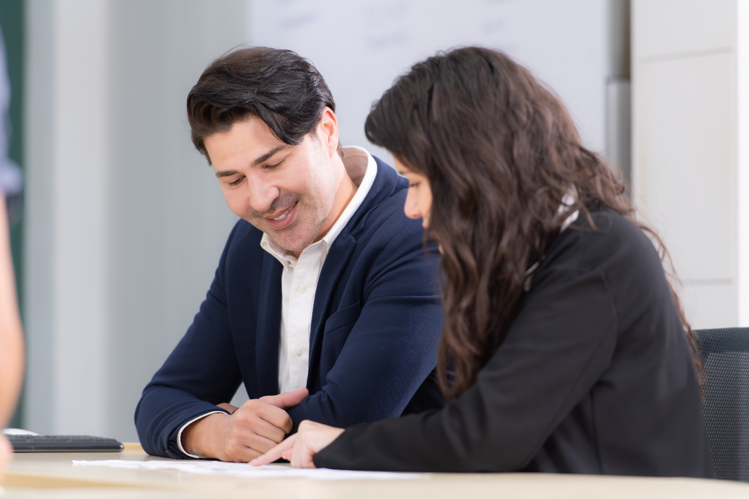 small-business-development-center-2 Consultores sonrientes del Small Business Development Center revisan documentos juntos en espacio iluminado y moderno.