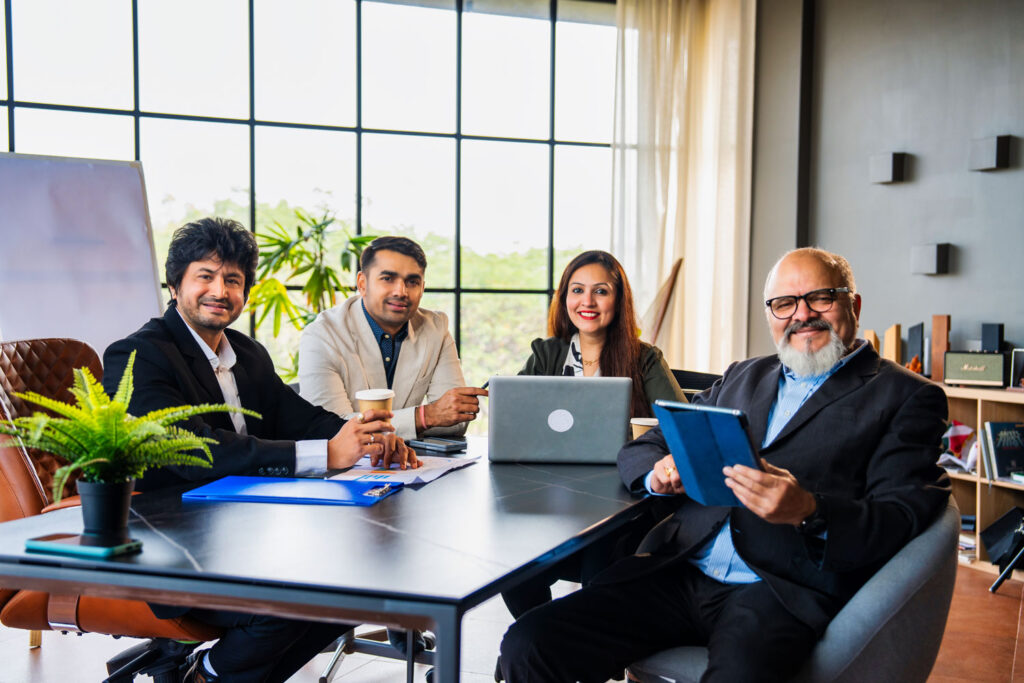Sentados en una mesa, en una sala de juntas hay personas hablando de alianzas estratégicas universidades empresas