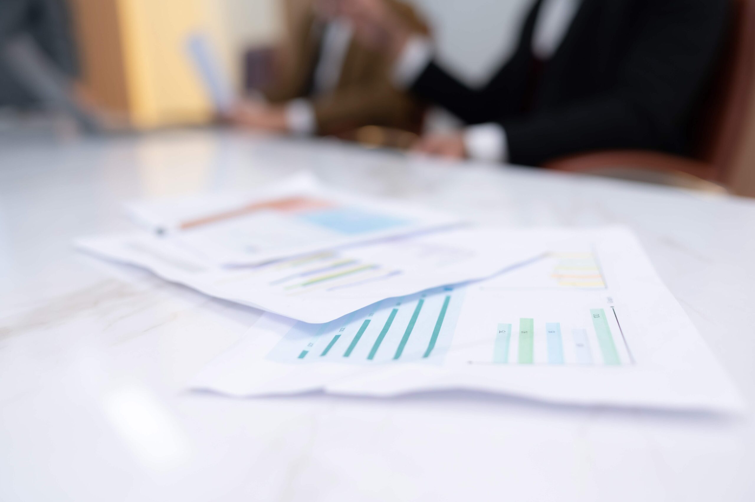 Reportes financieros con gráficas de barras en una mesa de juntas para definir como establecer precios de venta finales