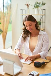 Software de facturación electrónica para PyMES Mujer frente a computadora organiza su negocio de moda usando sistemas de facturación electrónica desde su escritorio.