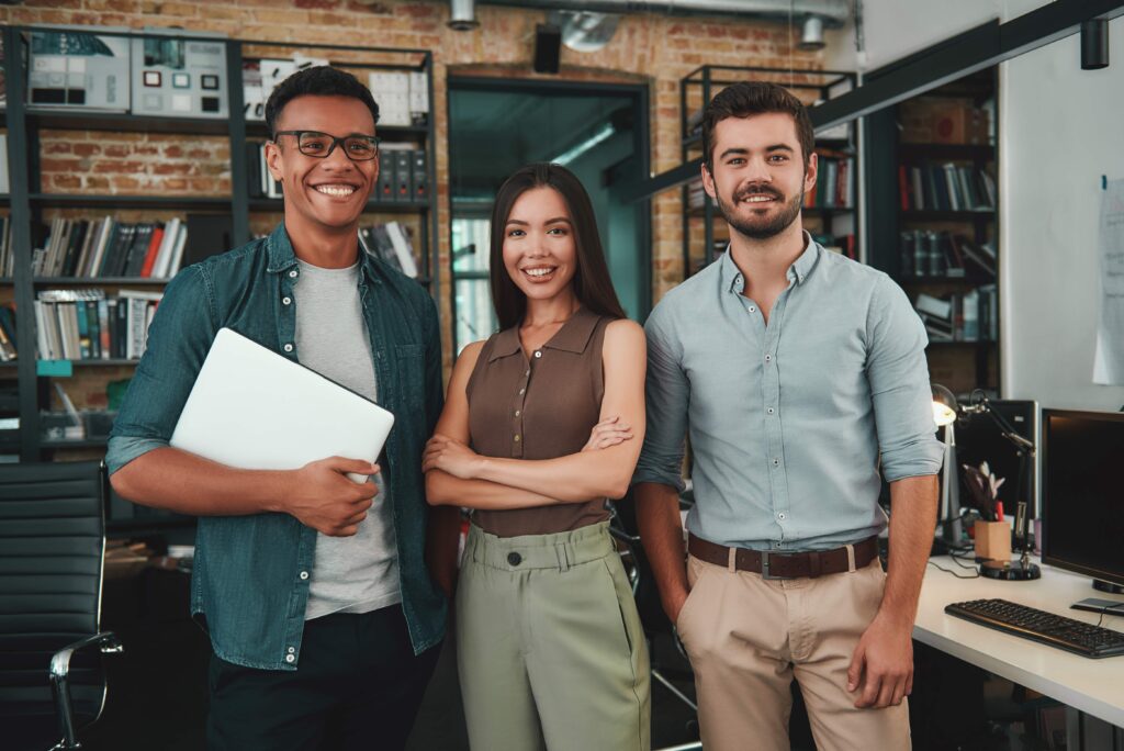 Socios jóvenes en una oficina moderna sonriendo mientras revisan los lineamientos de un protocolo familiar integral.