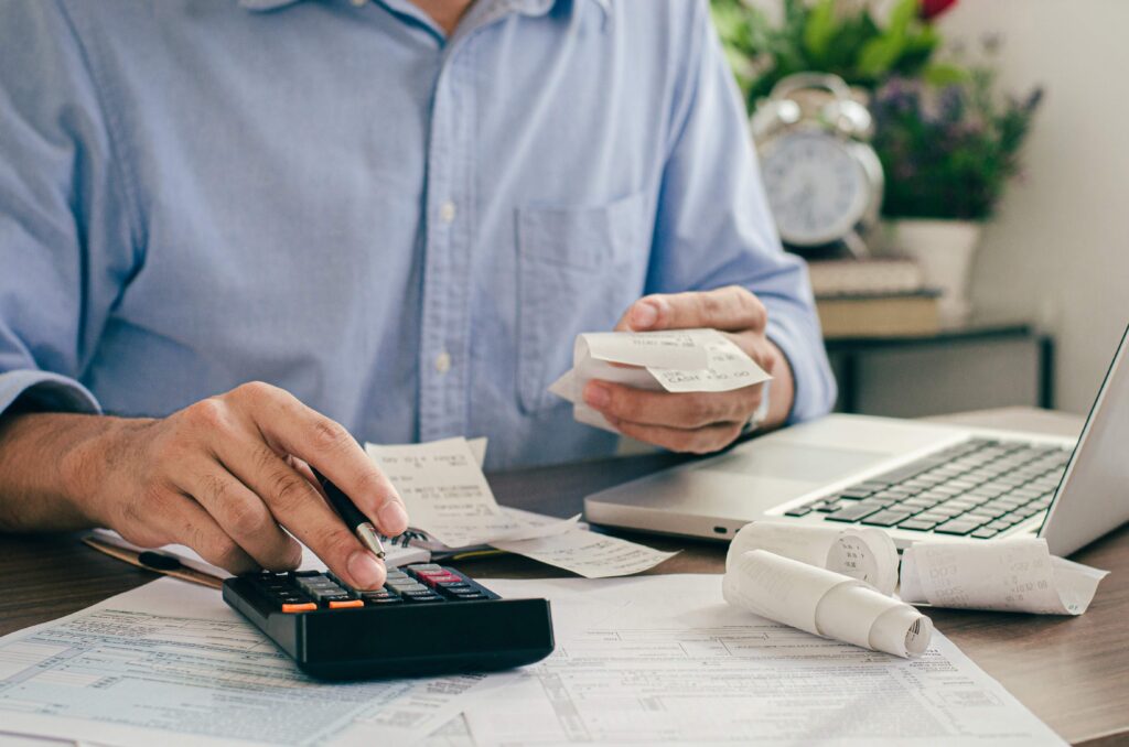 Contador utiliza calculadora y recibos físicos para organizar la facturación electrónica de una empresa en su oficina.