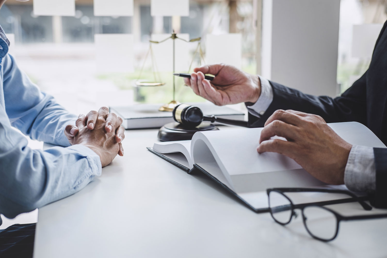 Servicios Especializados de Asesoría Legal y Financiera Abogado en consulta de asesoría legal y financiera revisando códigos jurídicos junto a un mazo de juez y una balanza