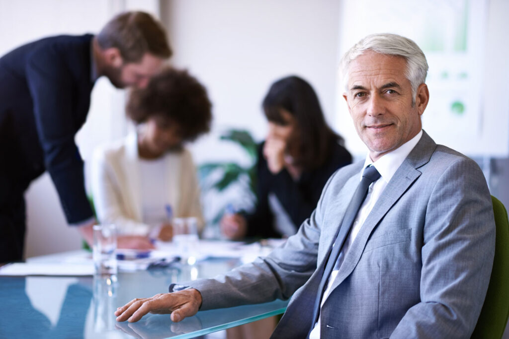 Retrato de un experimentado asesor de negocios liderando una junta directiva con su equipo de trabajo en el fondo
