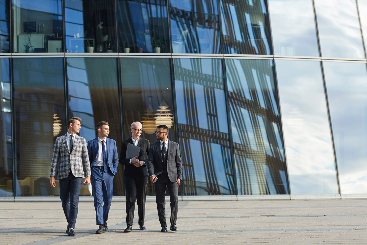 Impulsando la eficiencia mediante la optimización de procesos empresariales Profesionales caminando frente a oficinas modernas, enfocados en la optimización de procesos empresariales globales