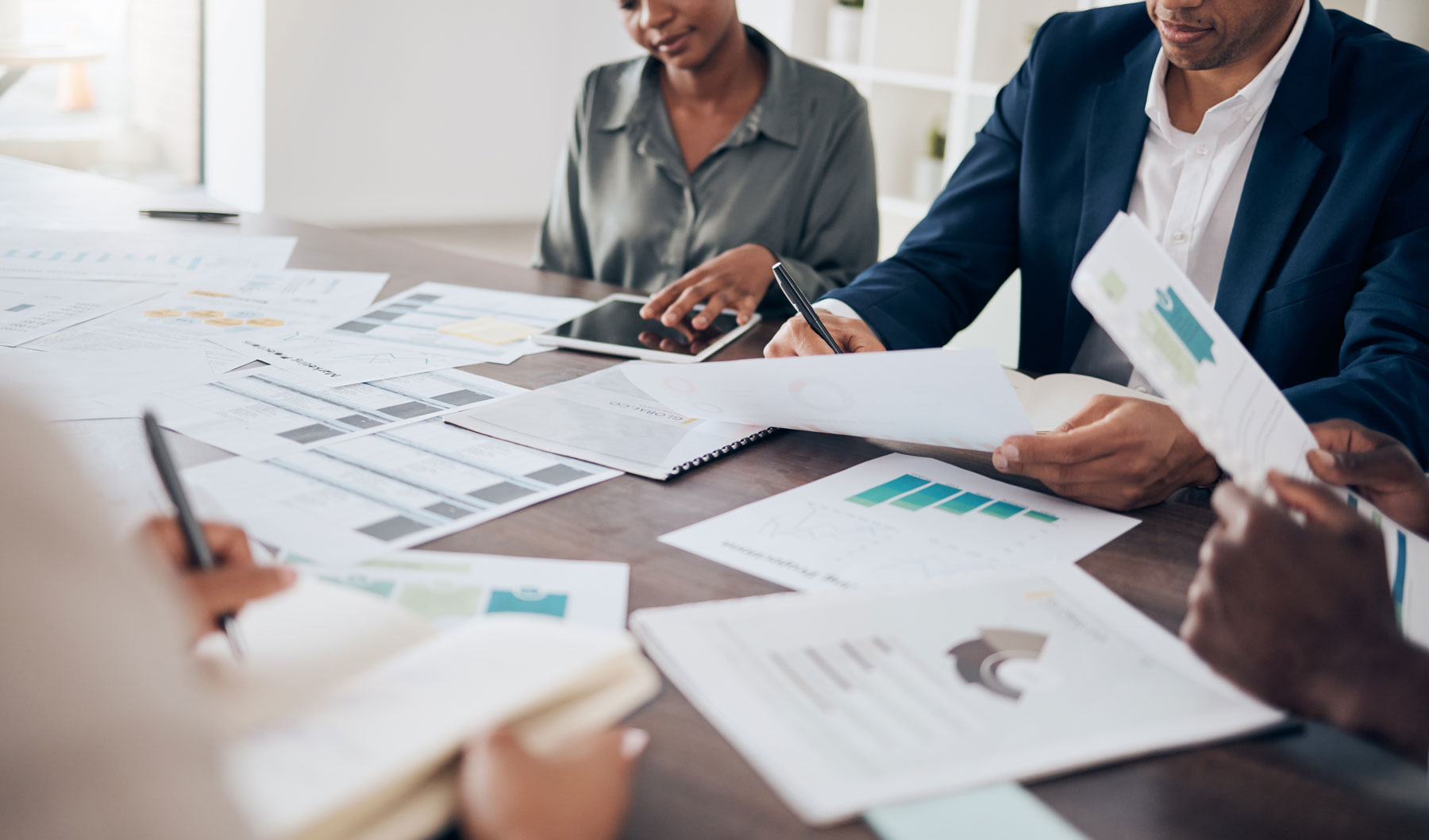 Gestión de Presupuesto Eficiente y Bootstrapping Emprendedores revisan documentos y tablet para la optimización de presupuesto mediante bootstrapping.