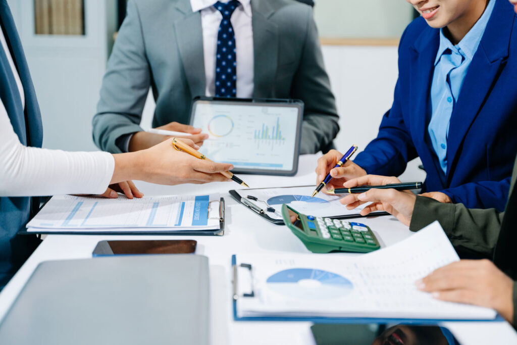 Manos de ejecutivos tomando notas y revisando documentos financieros sobre la planificación del flujo de caja cash flow.