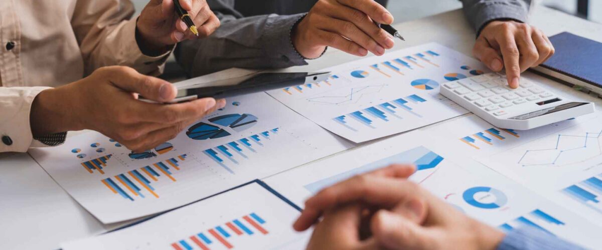 Evaluación de Estrategias de Inversión y Datos Financieros Equipo de profesionales analizando gráficos de barras y pastel para diseñar nuevas estrategias de inversión